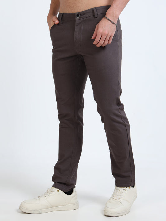 Person wearing dark gray pants and white sneakers on a white background