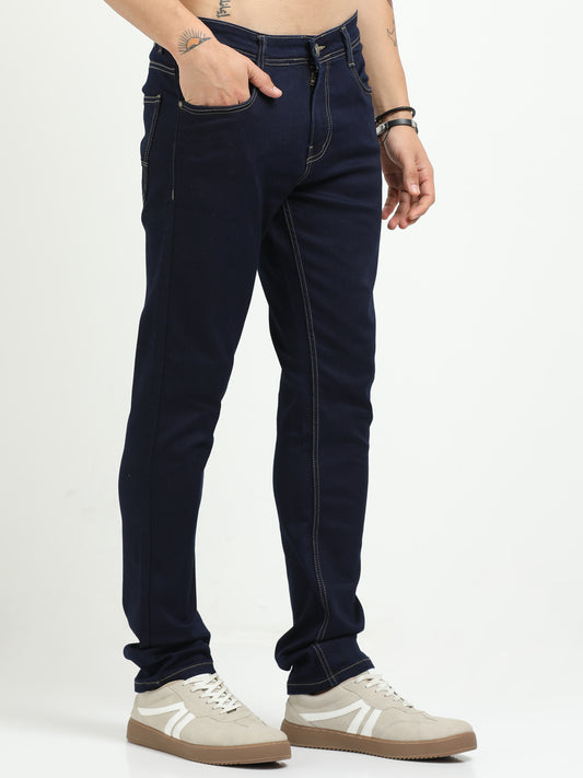 Person wearing dark blue jeans and beige sneakers on a white background