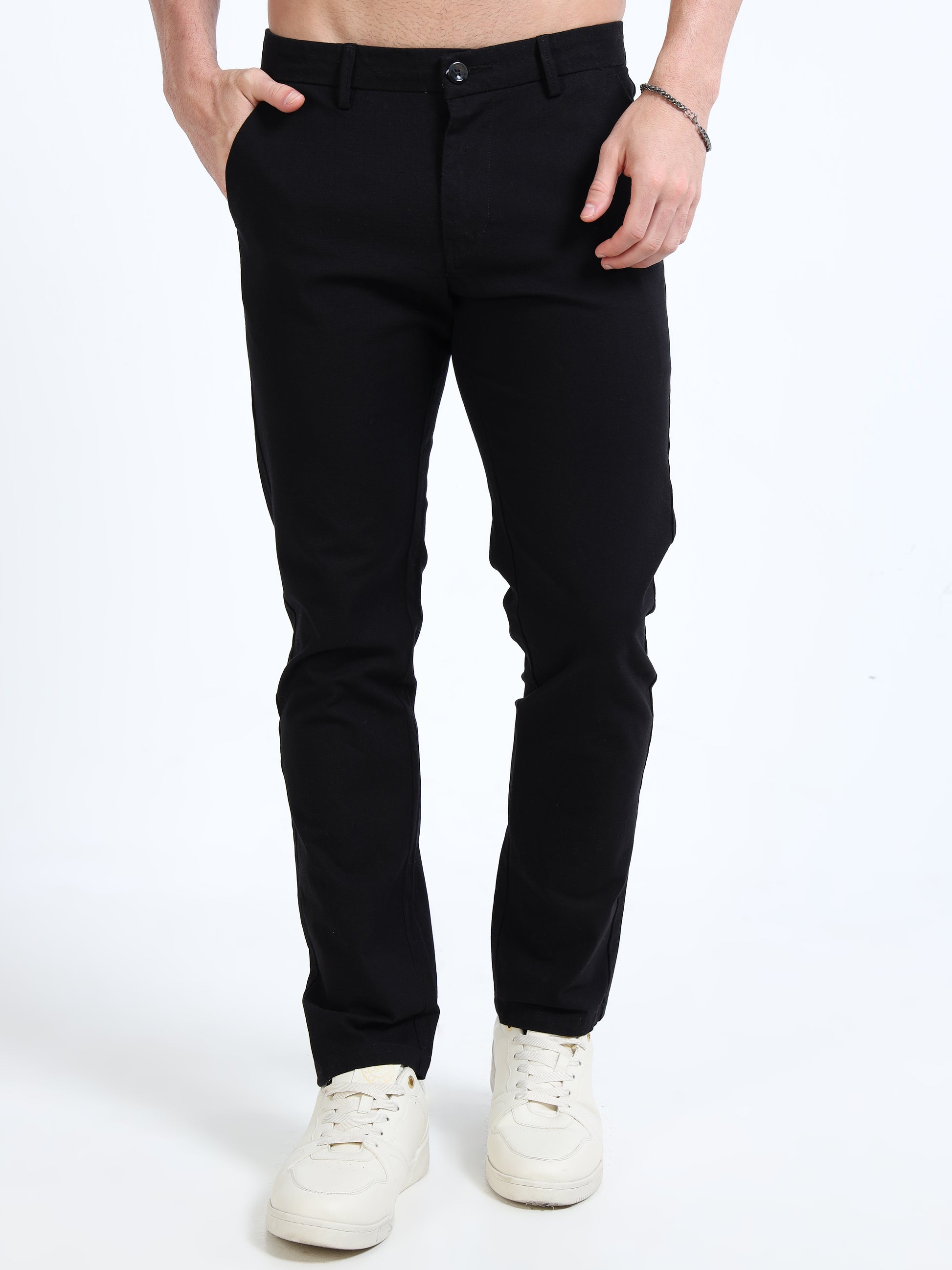 Person wearing black pants and white sneakers on a white background