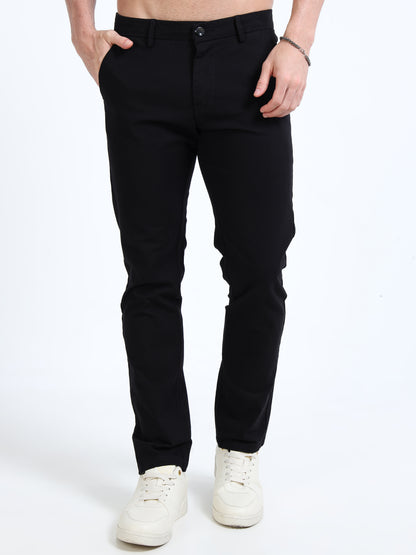 Person wearing black pants and white sneakers on a white background
